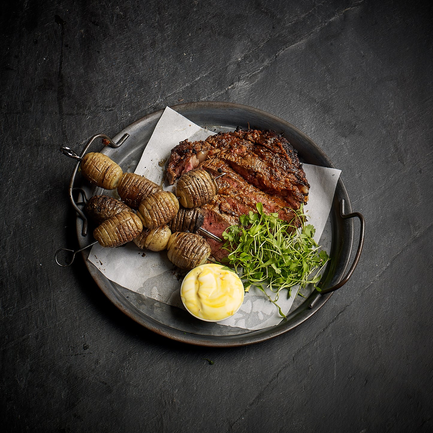 Vindaloo Iron Age Pork rib eye, cumin roasted hasselback potatoes with a honey yoghurt saffron dressing.