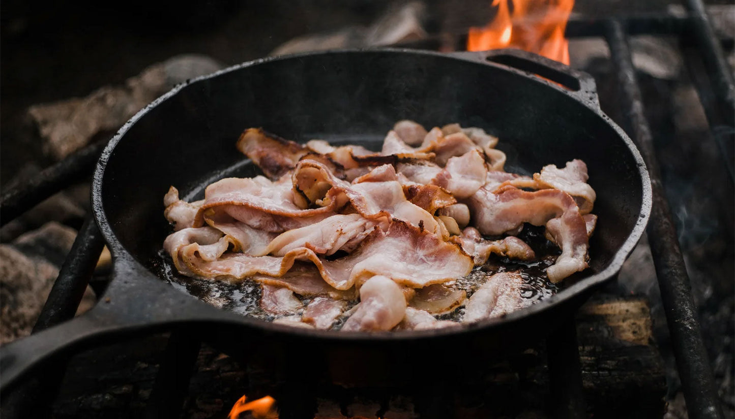 Bacon frying in a pan on an open fire